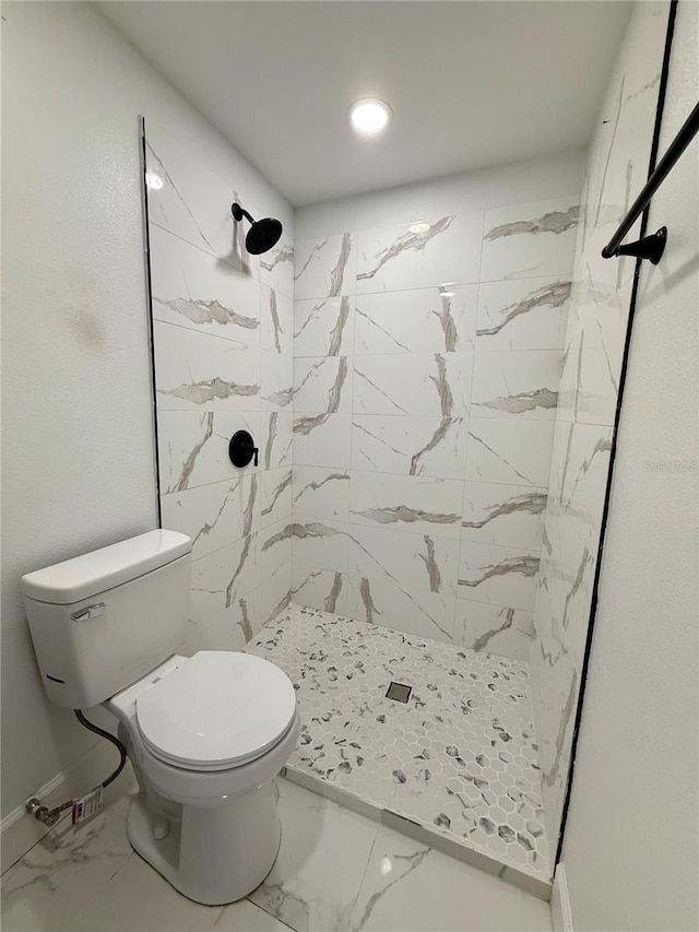 bathroom featuring a shower stall, toilet, baseboards, and marble finish floor