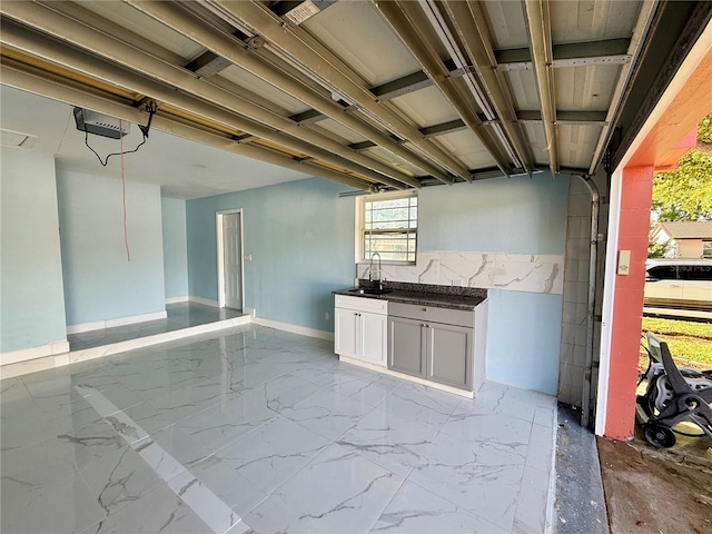 kitchen featuring dark countertops, white cabinets, marble finish floor, and a sink