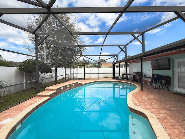 view of pool with glass enclosure, a patio area, a fenced backyard, and a fenced in pool