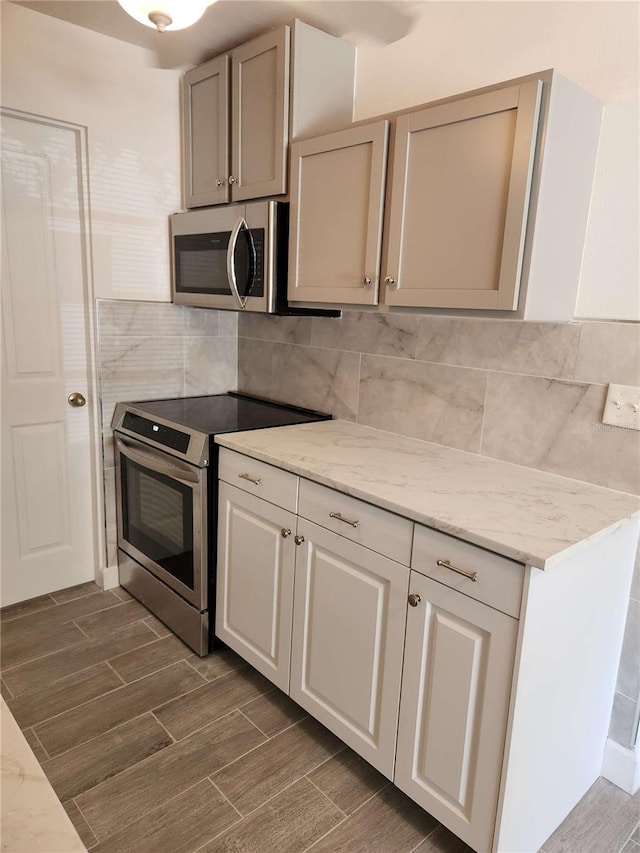 kitchen with light stone countertops, backsplash, and appliances with stainless steel finishes