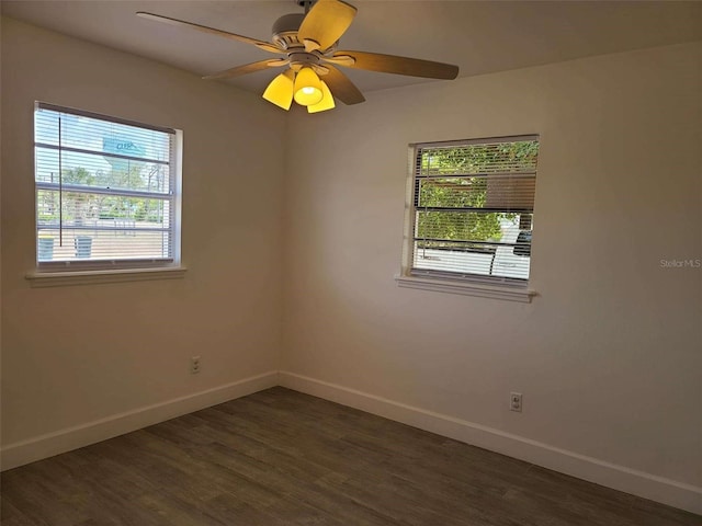 unfurnished room featuring dark wood-style floors, a wealth of natural light, and baseboards