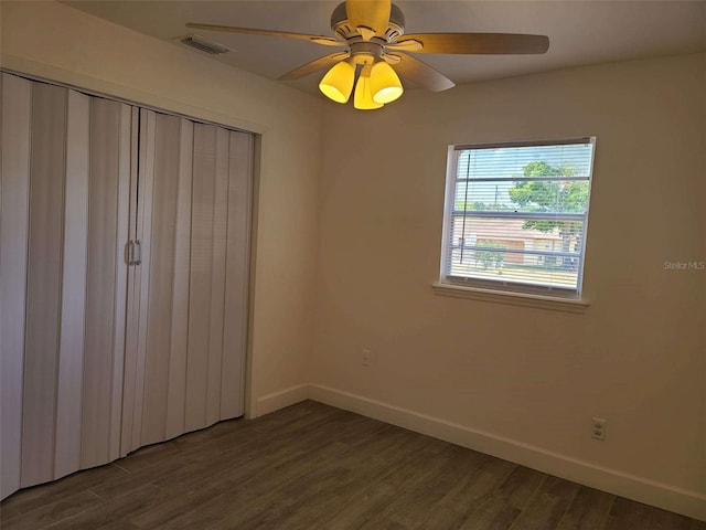 unfurnished bedroom featuring a closet, ceiling fan, baseboards, visible vents, and dark wood-style floors