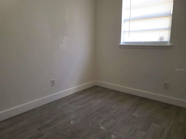 empty room featuring dark wood-type flooring and baseboards