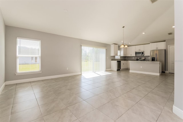 unfurnished living room with a wealth of natural light, baseboards, and light tile patterned flooring
