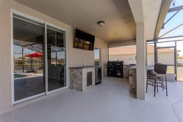 view of patio / terrace with beverage cooler, area for grilling, and a lanai