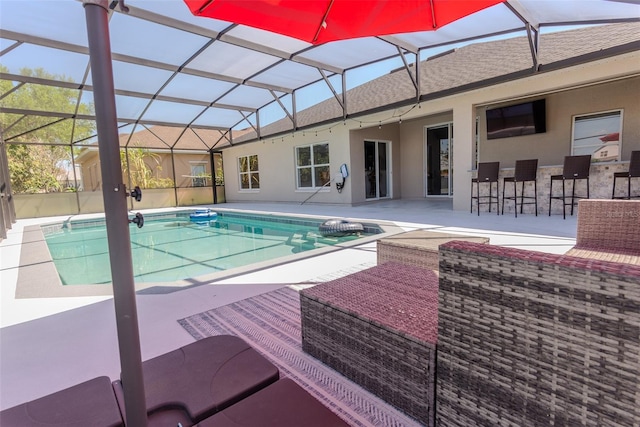 outdoor pool featuring a patio area, glass enclosure, and outdoor dry bar