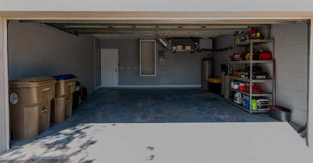 garage with electric panel, gas water heater, and concrete block wall