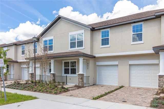 view of front of home with stucco siding, decorative driveway, a garage, and covered porch