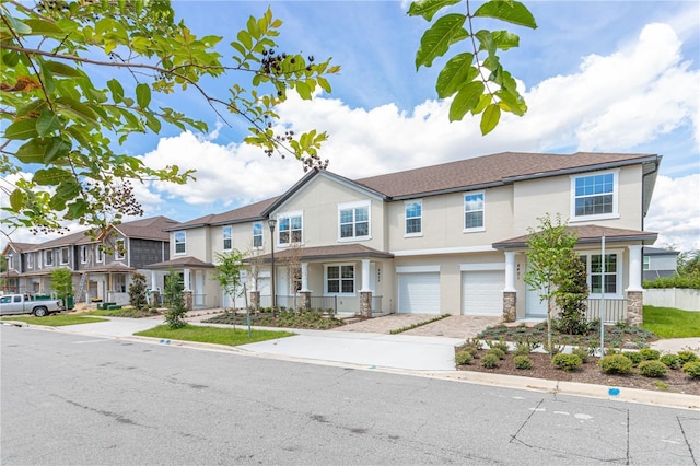 view of property featuring a garage, a residential view, driveway, and stucco siding