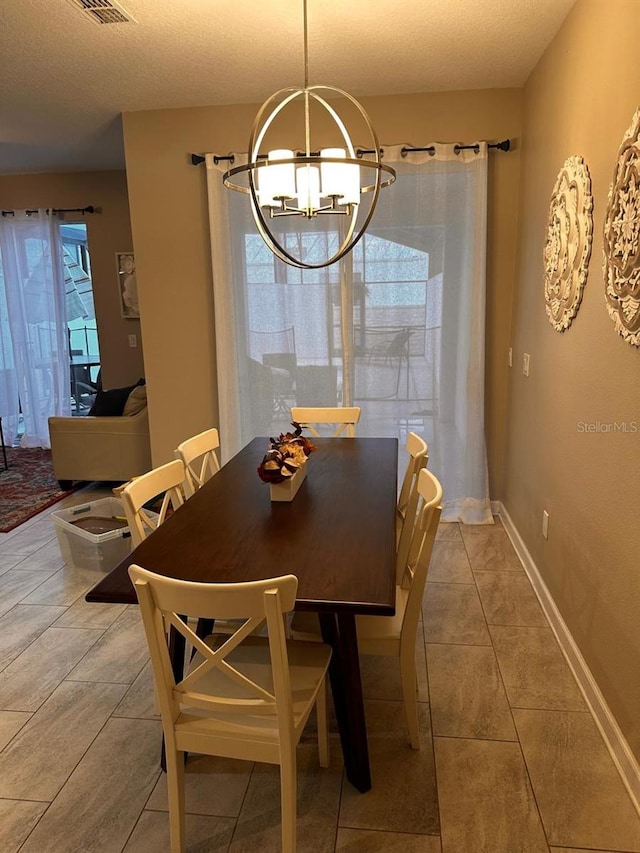 dining space featuring visible vents, a textured ceiling, light tile patterned floors, baseboards, and a chandelier