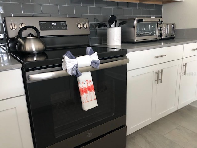 room details featuring a toaster, decorative backsplash, white cabinetry, and electric stove