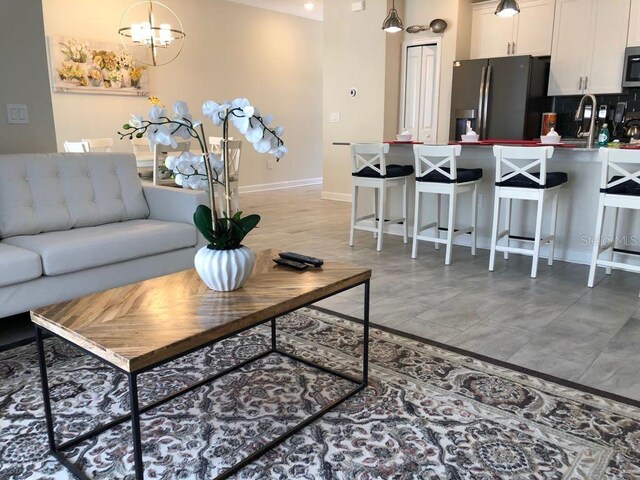 living area featuring baseboards and an inviting chandelier