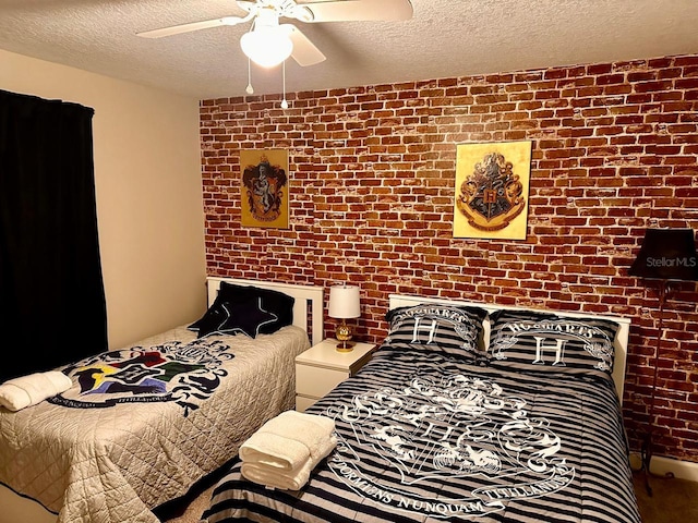 bedroom featuring a ceiling fan, brick wall, and a textured ceiling