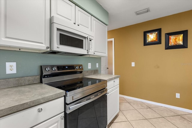 kitchen with white microwave, visible vents, light tile patterned flooring, stainless steel electric range, and white cabinets