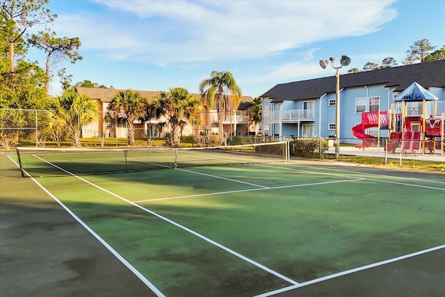 view of tennis court with fence and a residential view