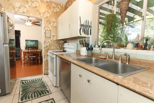 kitchen with plenty of natural light, a sink, wallpapered walls, and appliances with stainless steel finishes