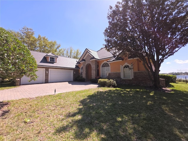 view of front of home featuring a garage, a front lawn, decorative driveway, and stone siding