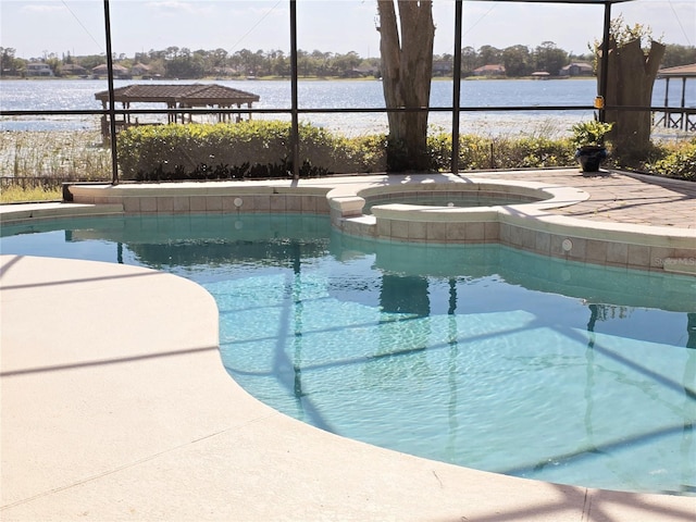 view of pool with a lanai, a pool with connected hot tub, a patio, and a water view