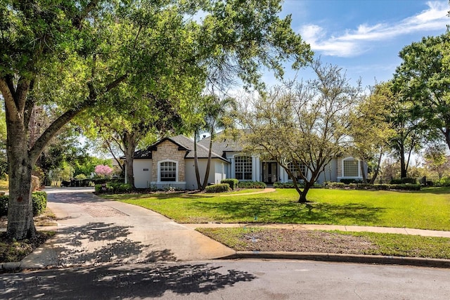 ranch-style home featuring a front lawn, driveway, and stucco siding