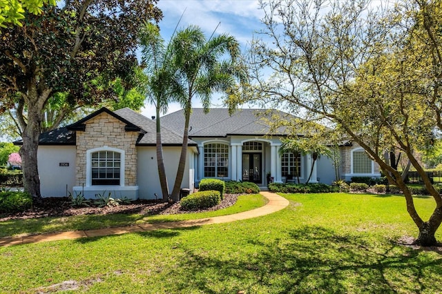 view of front of home featuring french doors, stone siding, a front lawn, and a shingled roof