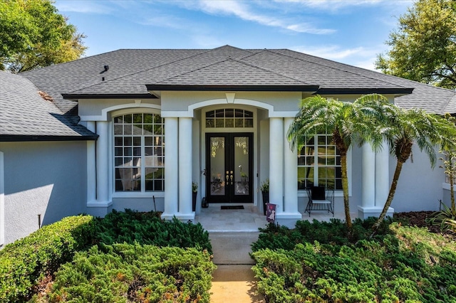 property entrance with french doors, roof with shingles, and stucco siding