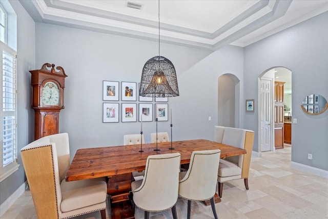 dining area featuring visible vents, a raised ceiling, arched walkways, and baseboards