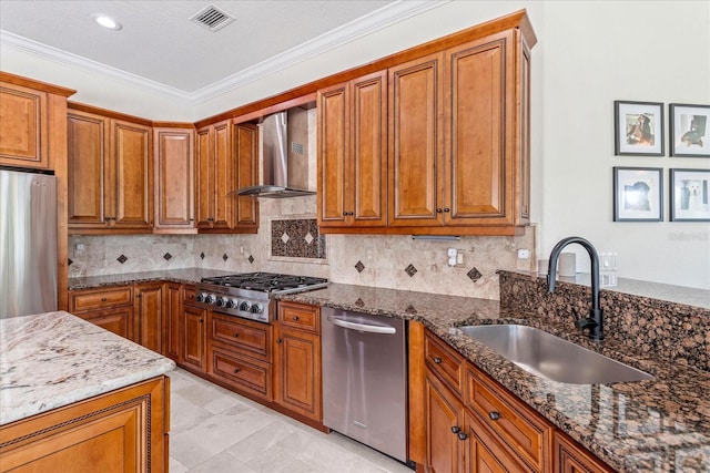 kitchen featuring visible vents, brown cabinets, a sink, appliances with stainless steel finishes, and wall chimney exhaust hood