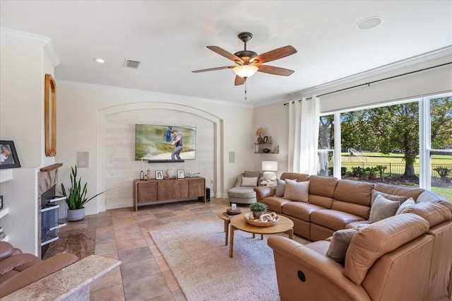 living room with crown molding, baseboards, visible vents, and ceiling fan