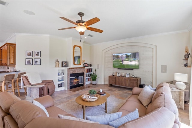 living area featuring ornamental molding, a fireplace, visible vents, and ceiling fan