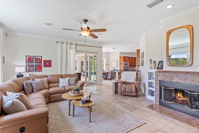 living room featuring a high end fireplace, visible vents, crown molding, and ceiling fan