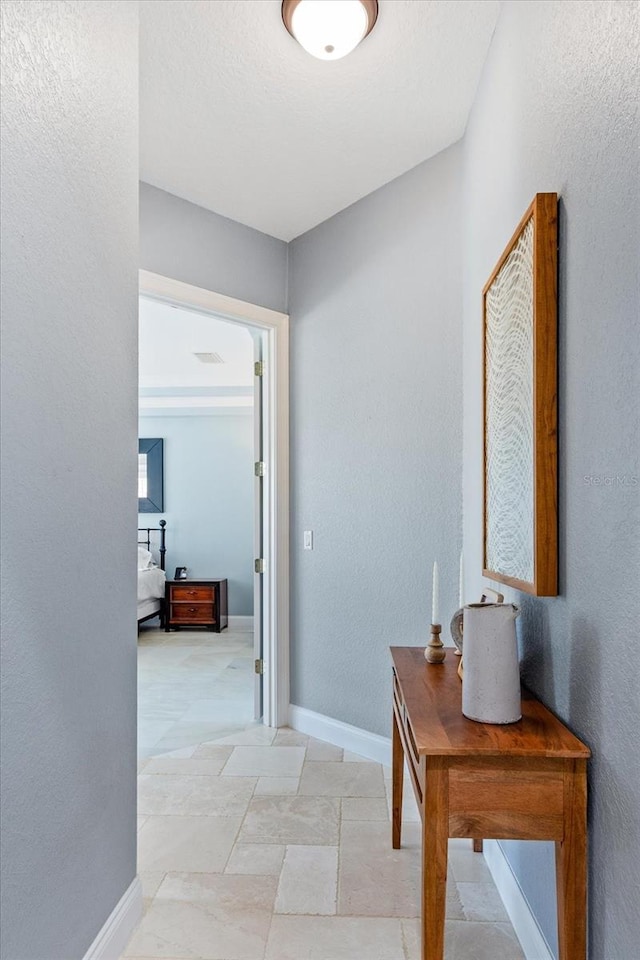 corridor with baseboards and a textured wall