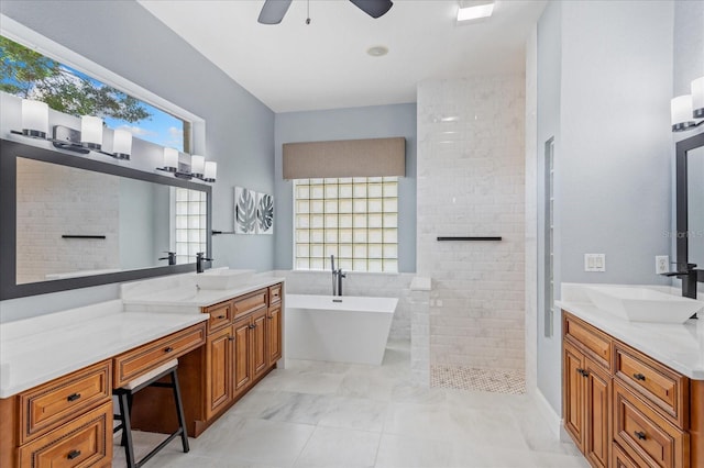 full bath featuring a walk in shower, ceiling fan, two vanities, a soaking tub, and a sink