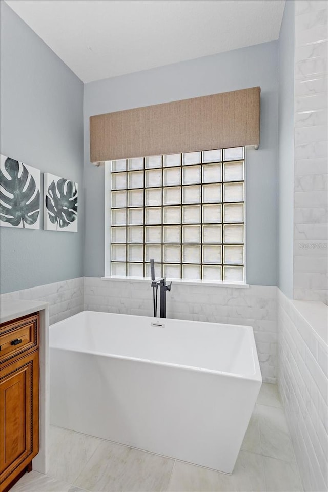 full bathroom featuring tile walls, a soaking tub, and a wainscoted wall