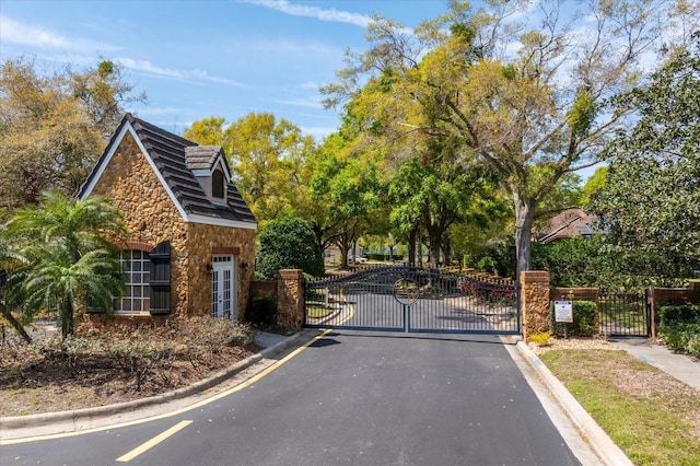 view of street featuring a gated entry, curbs, and a gate