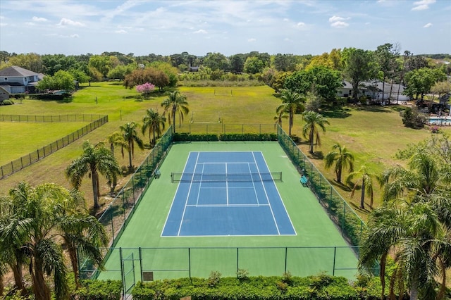 view of sport court with a rural view, fence, and a lawn