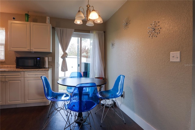 dining space with dark wood-style floors, a notable chandelier, baseboards, and a textured wall