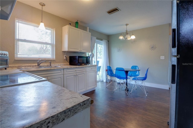 kitchen featuring visible vents, dark wood finished floors, white cabinetry, freestanding refrigerator, and a chandelier