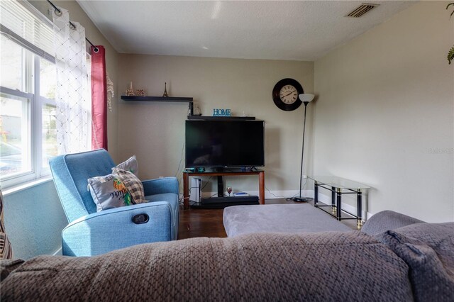 living room with wood finished floors, visible vents, and baseboards