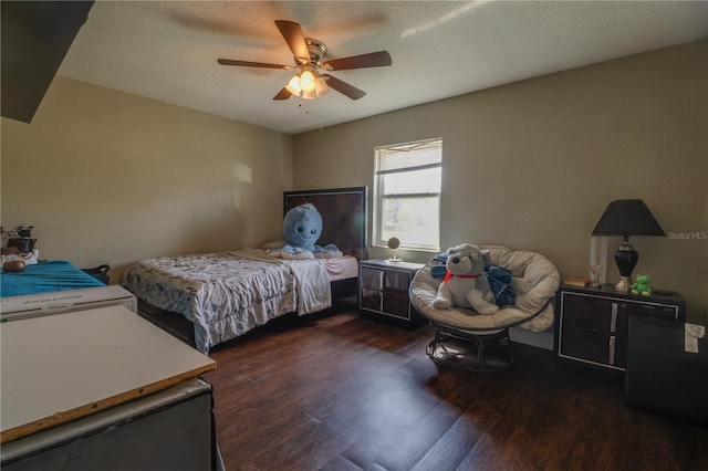 bedroom featuring a ceiling fan, wood finished floors, a textured wall, and a textured ceiling