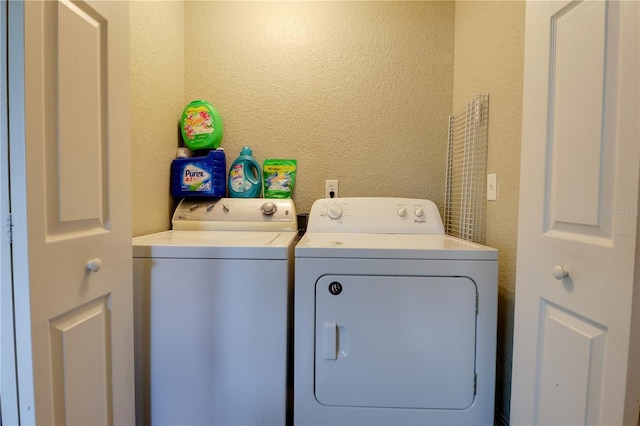 washroom with washer and dryer, laundry area, and a textured wall