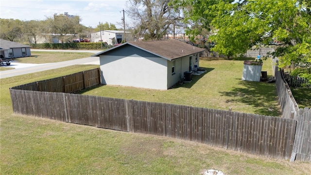 view of home's exterior with central AC unit, a lawn, a fenced backyard, and stucco siding