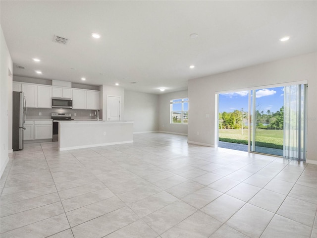 unfurnished living room with baseboards, recessed lighting, visible vents, and a sink