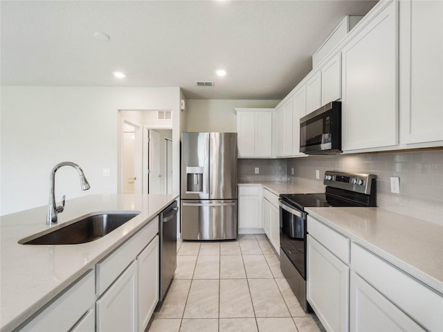 kitchen featuring visible vents, a sink, decorative backsplash, stainless steel appliances, and white cabinetry