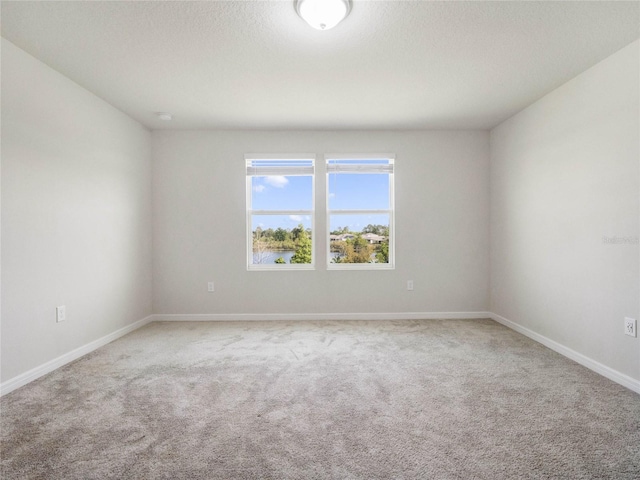 carpeted empty room featuring baseboards and a textured ceiling