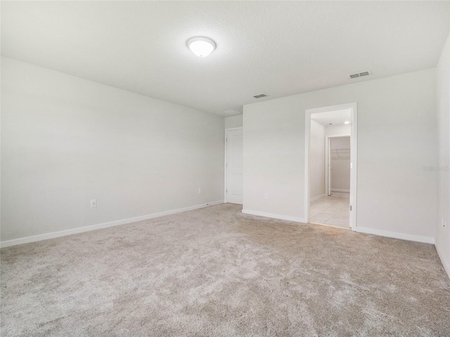 empty room with visible vents, light carpet, and baseboards