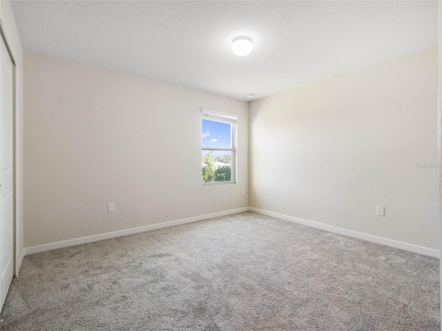 spare room featuring carpet flooring and baseboards