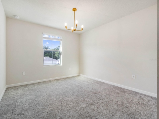 carpeted spare room with baseboards and an inviting chandelier