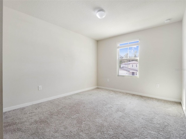 unfurnished room with baseboards and carpet flooring