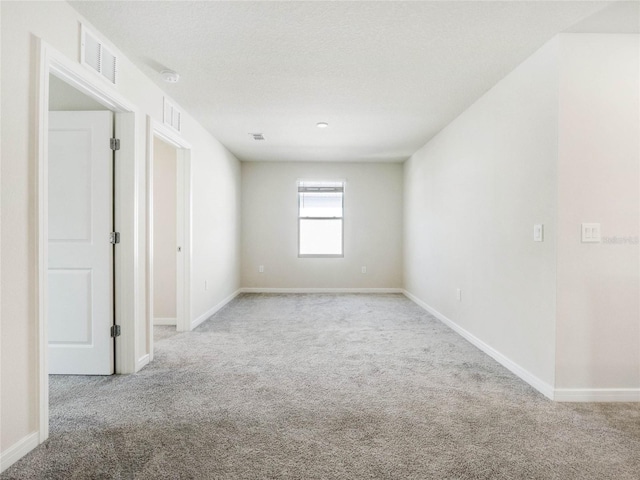 unfurnished room featuring visible vents, baseboards, and carpet