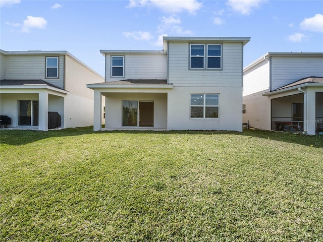 rear view of property featuring a lawn and stucco siding